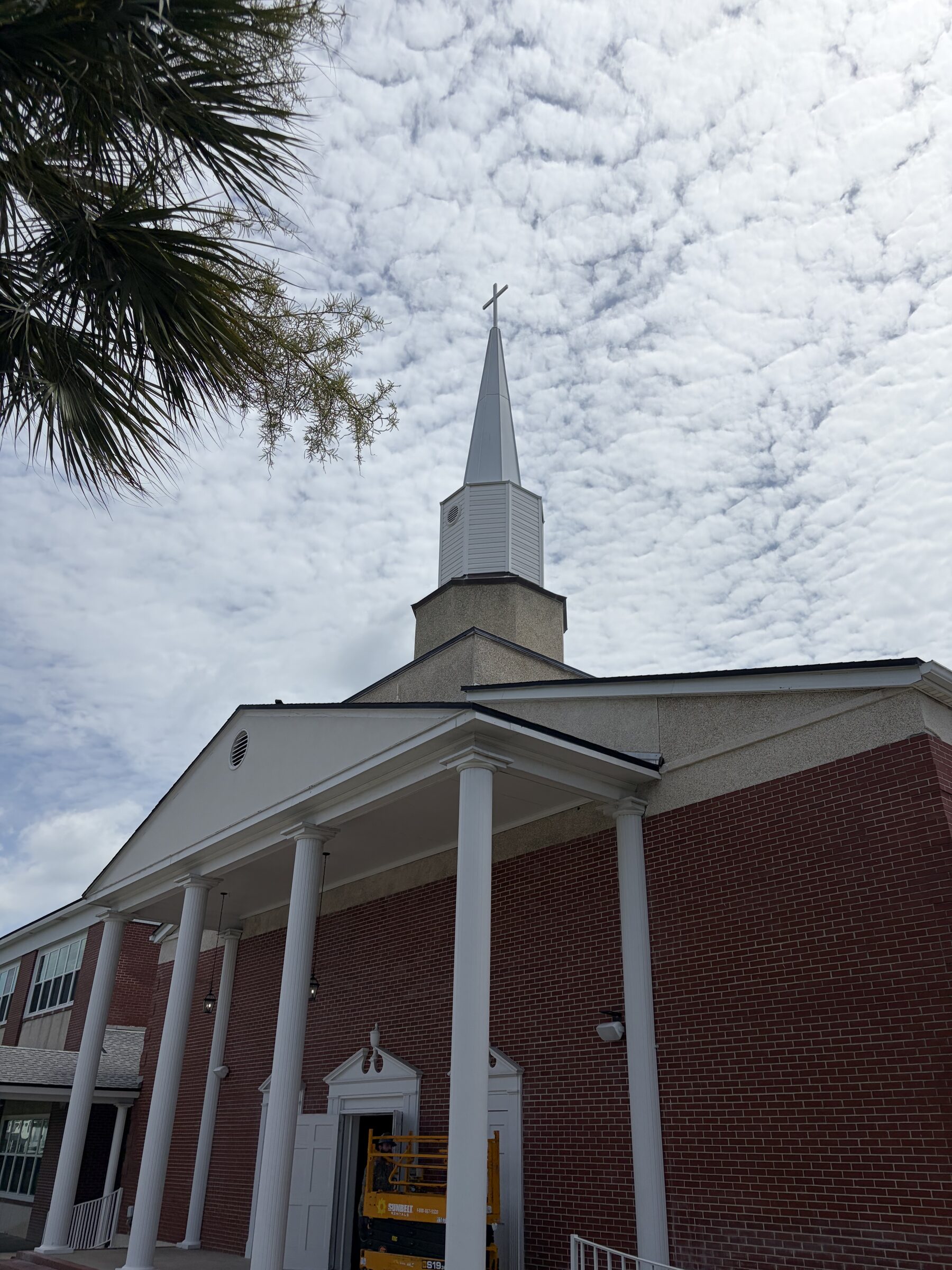 Brick church with a white steeple during renovation in Neptune Beach, Florida